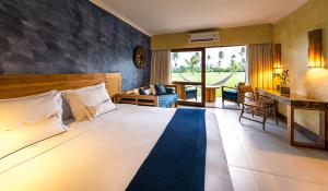 a bedroom with a large bed and a living room at Tivoli Ecoresort Praia do Forte in Praia do Forte
