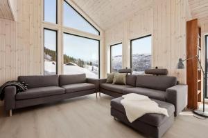 a living room with a couch and a chair and windows at Hodlekvevegen 308 - Flott hytte midt i skisenteret in Sogndal