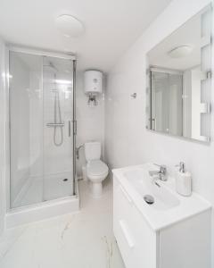 a white bathroom with a shower and a toilet at VIPoL Pokoje Biznesowe in Łódź