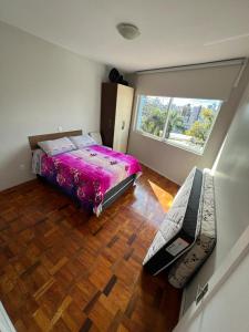 Un dormitorio con una cama grande y una ventana en Ap 3 qts, a suíte e mais 1 qt com split, en Bento Gonçalves