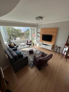 uma sala de estar com sofás e uma televisão de ecrã plano em Ap 3 qts, a suíte e mais 1 qt com split em Bento Gonçalves