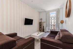 ein Wohnzimmer mit einem Sofa und einem TV in der Unterkunft BNBHolder Apartamentos en Sol Confort 9 in Madrid