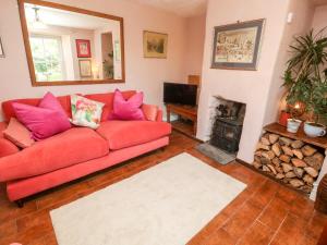 a living room with a red couch and a fireplace at Pentira in Helston