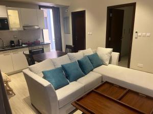 uma sala de estar com um sofá branco com almofadas azuis em Glory Salalah Miko 1 em Salalah