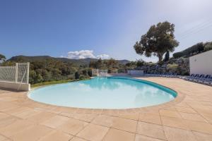 una piscina en un patio con montañas al fondo en Capra Scorsa - Appt vue mer et piscine partagée, en Belgodère