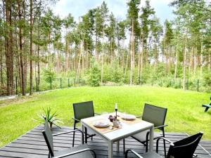 einen Tisch und Stühle auf einer Holzterrasse mit einem Hof in der Unterkunft Leśny Azyl in Kępiaste