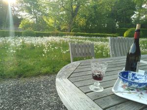 Huisseau-sur-CossonにあるLa Taille de Biouの木製テーブルにワイン1本とグラス1杯