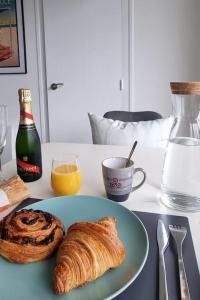 een tafel met een bord croissants en een fles champagne bij Océan bleu - Studio bord de plage in La Baule