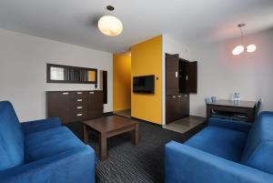 a living room with two blue couches and a table at Golden Tulip Gdańsk Residence in Gdańsk