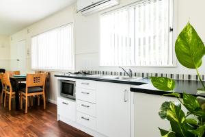 a kitchen with white cabinets and a table at The Retreat Port Stephens in Anna Bay