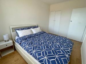 a bedroom with a bed with a blue and white comforter at Central Apartment near Dandenong Hospital & Market in Dandenong
