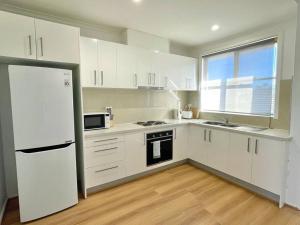 a kitchen with white cabinets and a white refrigerator at Central Apartment near Dandenong Hospital & Market in Dandenong