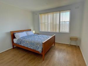 a bedroom with a bed and a window at Central Apartment near Dandenong Hospital & Market in Dandenong