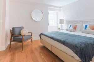 a bedroom with a bed and a chair and a mirror at Downtown Charming Apartments - Apartamento Castelo in Chaves