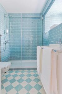 y baño con ducha, aseo y azulejos azules. en Downtown Charming Apartments Apartamento Castelo, en Chaves