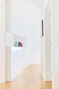 a white kitchen with white cabinets and a wooden floor at Downtown Charming Apartments Apartamento Castelo in Chaves