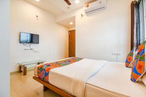 a bedroom with a bed and a tv on the wall at FabHotel The Address in Nashik