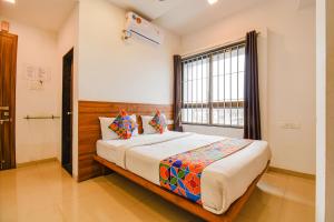 a bedroom with a large bed with a window at FabHotel The Address in Nashik