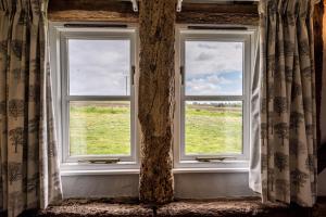 an open window with a view of a field at The Hayloft Valley Farm Barns Snape Air Manage Suffolk in Saxmundham