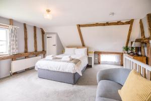 a bedroom with a large bed and a couch at The Hayloft Valley Farm Barns Snape Air Manage Suffolk in Saxmundham