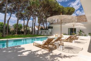 una piscina con sillas y sombrillas junto a una casa en Anfitrión Villas & Suites, en Marbella