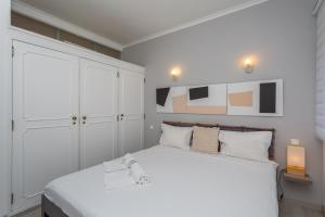 a bedroom with a large white bed and a white cabinet at BeGuest Gandarinha Apartment in Cascais