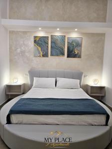 een slaapkamer met een groot bed met drie schilderijen aan de muur bij My Place Apartments in Policoro