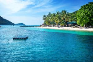 a boat in the water next to a beach at Tuna Bay Island Resort in Perhentian Islands