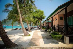 a beach with palm trees and a building at Tuna Bay Island Resort in Perhentian Islands