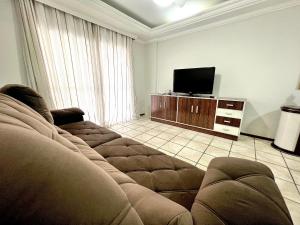 een woonkamer met een bank en een flatscreen-tv bij Jurere in Meia Praia