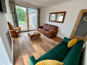 a living room with a green couch and leather furniture at Spacious Family home in Cardiff with Parking! in Cardiff