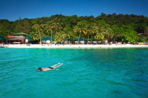 a person swimming in the water in front of a beach at Tuna Bay Island Resort in Perhentian Islands