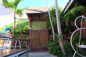 a wooden entry door to a house with palm trees at Baan Wassana In The City Old Moat in Chiang Mai