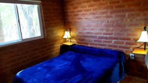 una camera con un letto blu e due lampade di Cabaña El Chaparral Villa Dolores, Traslasierra 1 a Piedra Pintada