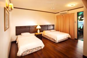 two beds in a hotel room with a window at Tuna Bay Island Resort in Perhentian Islands