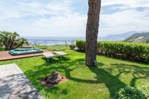 un patio con un árbol y un banco y el océano en Villa with Sea View Jacuzzi, en Vallecrosia