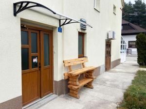 a wooden bench sitting outside of a building at Apartman Kraljica 2 in Kupres