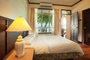 a bedroom with a bed with a lamp and a window at Tuna Bay Island Resort in Perhentian Islands