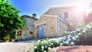 una casa de piedra con una puerta azul y algunas flores en Antico Borgo, en Arcevia