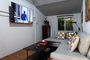 a living room with a white couch and a flat screen tv at Baan Wassana In The City Old Moat in Chiang Mai