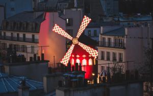 un molino de viento iluminado en una ciudad por la noche en Studio Montmartre, en París