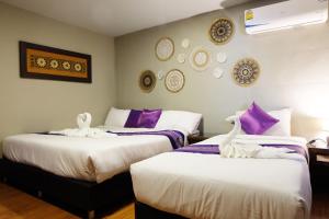 two beds in a room with swans on them at Baan Wassana In The City Old Moat in Chiang Mai +42 photos