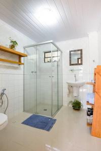 uma casa de banho com uma cabina de duche em vidro e um lavatório. em Canto da Floresta em Monte Verde