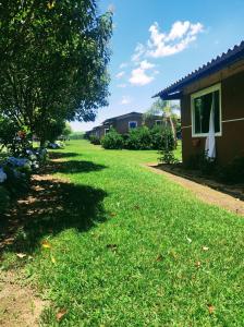 podwórko z domem, drzewem i trawą w obiekcie Cachoeira do Alemão - Recanto dos Arcos w mieście Balsa Nova