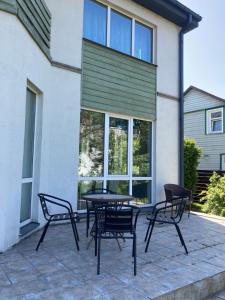 Un patio con sillas y una mesa frente a un edificio. en Holiday House near beach, en Liepāja 3 fotos más