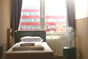 a bedroom with a bed and a window with a fan at Hostel City Süd in Hamburg