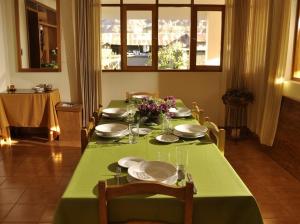 a table with a green table cloth and plates and flowers at Posada Las Tres Marias in Urubamba