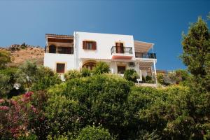 a white house on top of a hill with trees at Yvonni Studios in Patmos