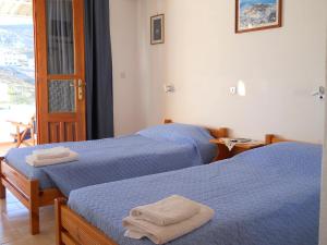 duas camas num quarto de hotel com toalhas em Yvonni Studios em Patmos