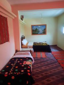 a room with two beds and a rug at Auberge l' avenir in Imilchil